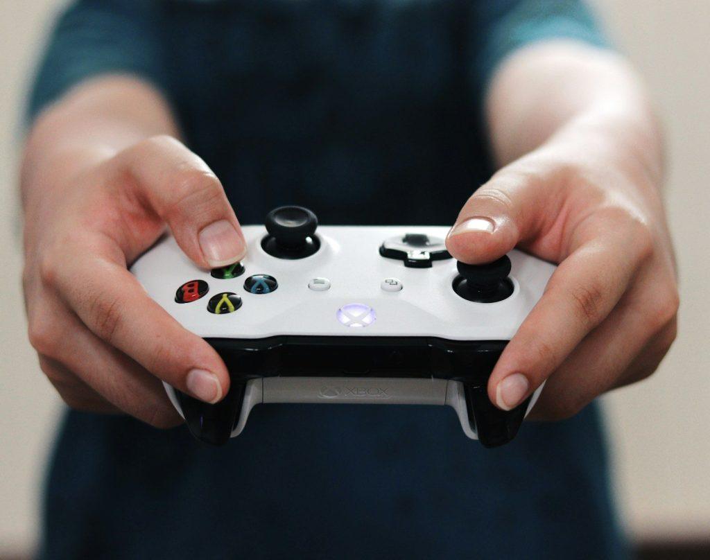 person holding white and black xbox one game controller