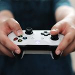 person holding white and black xbox one game controller