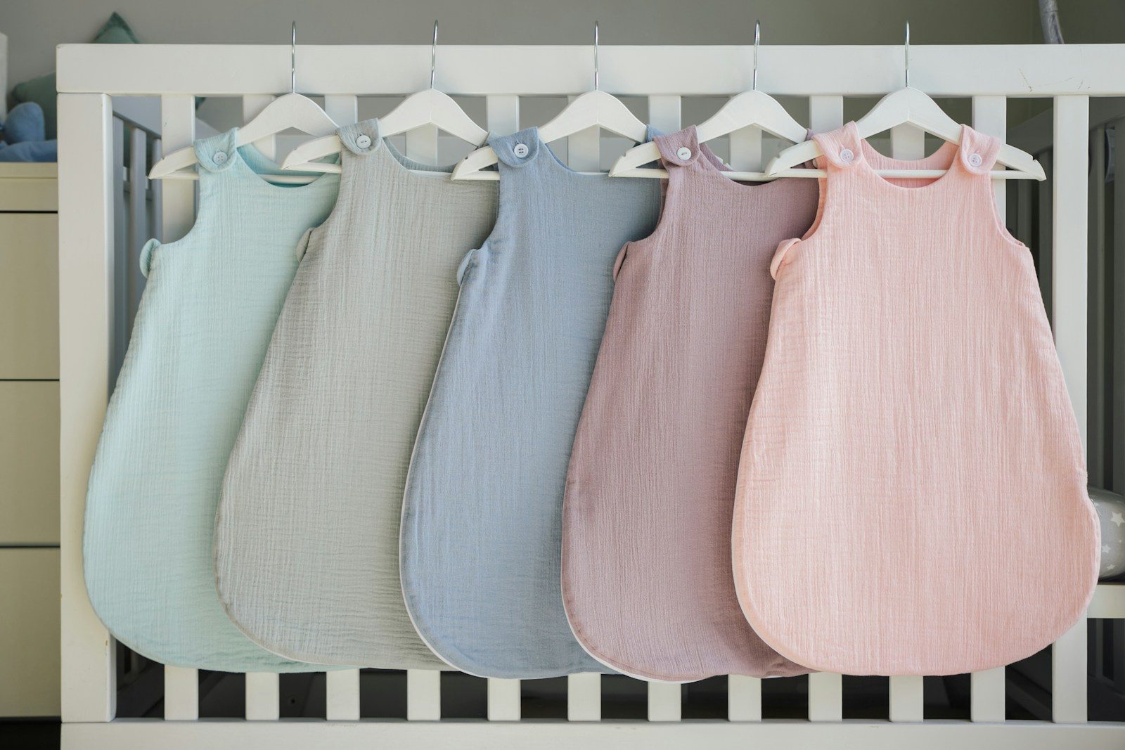 a row of baby swaddles hanging from a crib